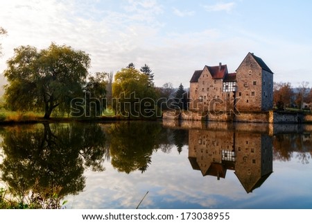 Lovely medieval water castle Brennhausen in Bavaria, Germany with reflections in the water  Landscape and Architecture Picture of this ancient building was taken in Fall on a warm morning in Europe