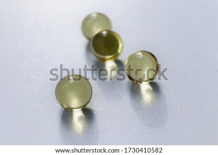 
Transparent round capsules of vitamins - Fish oil pills close-up. Small gold-yellow balls on a white background. Concept of treatment and prevention of health. 