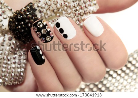 Manicure on short nails covered with black and white lacquered with rhinestones on a black background  Royalty-Free Stock Photo #173041913