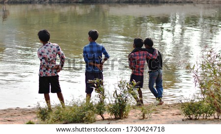 Four friends watching  something on the other side of river.
