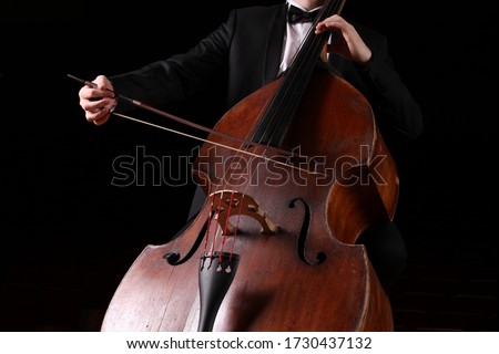 Hands of a musician with a bow playing the double bass Royalty-Free Stock Photo #1730437132