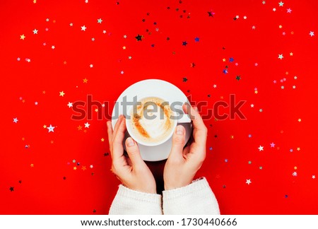 Hand and cup of coffee, red color background with sparkles