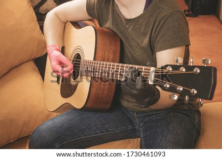 Close-up of a guy playing guitar on the couch at home. Stay at home. Toned. Selective focus on the hand with the pick and strings . Make music