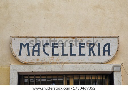 Close-up of a rusty metal shop sign with the Italian writing: "Macelleria", translation: "Butchery", on the wall of an old building, Italy