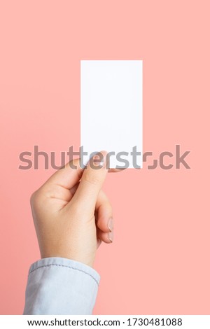 Female hands with cutaway, blank menu, discount card, business card on color pink beauty background with copy space. Template for design. Vertical photo. Mockup