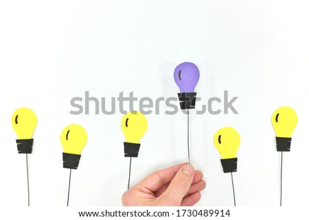 New innovation, unique business idea and game changer concept. Hand holding a different color light bulb.