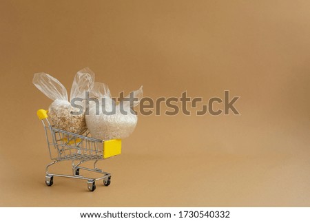 various groats in packages in a grocery cart on a brown background. Rice and oatmeal