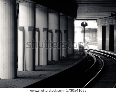 Black and white picture of the subway train tunnel with light in the end.
