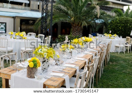 Wedding table setting on a long wood table with yellow flowers