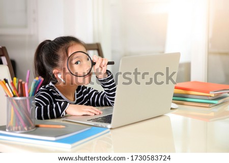 The asian little girl is studying online at home with her computer.