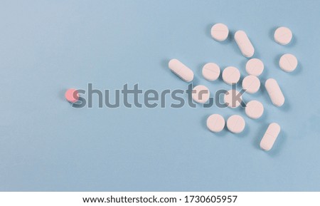 White pills are located in a group and one red pill on a blue background. Copyspace for text