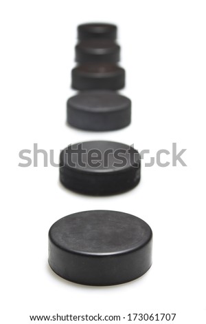 A series of hockey pucks with one in sharp focus