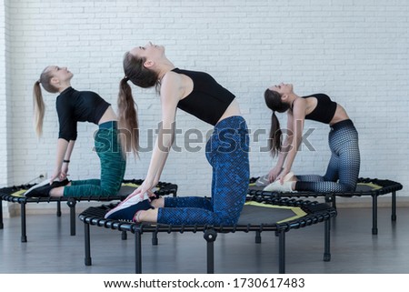 Yoga time concept. Two young women on trampoline, young fitness girls trains on a fitness studio.