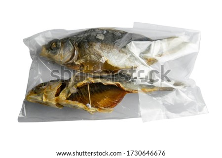 Dried salted crucian fishes in a transparent package isolated on white background. Snack to beer.