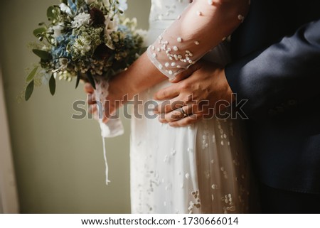 photo of a wedded couple standing next to the window