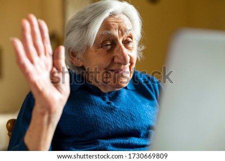 Authentic shot of a happy grandmother is making a video call to relatives with a laptop at home. Concept of technology, modern generation,family, connection, authenticity Royalty-Free Stock Photo #1730669809