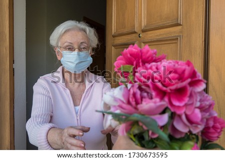Senior woman with protective mask gets flowers on mothers day Royalty-Free Stock Photo #1730673595