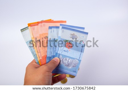 Man Hand Holding Malaysia Bank Notes on White Background.