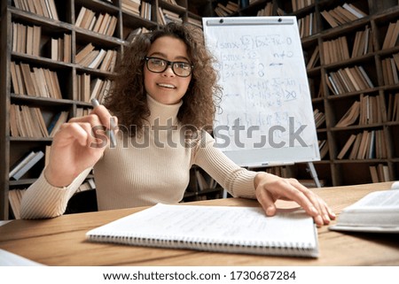 Female young hispanic school math teacher, college tutor coach looks at camera in classroom speaking virtual teaching remote class, online lesson, elearning video conference zoom call. Webcam view. Royalty-Free Stock Photo #1730687284