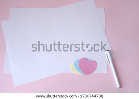 White blank greeting card and pen on light pink background, colored love decoration