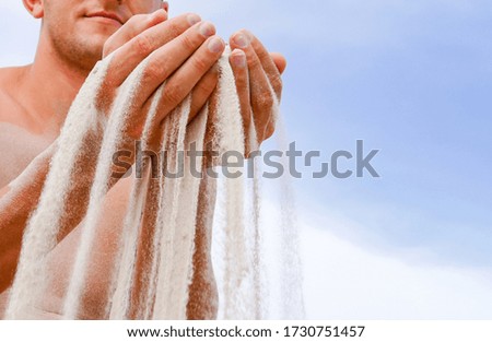 sand pours through the fingers of a man
