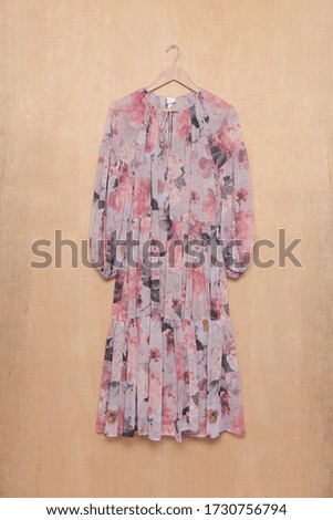 Woman fashion long floral pattern dress on hanging-WOODEN BACKGROUND


