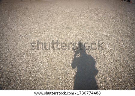 Shadow of man holding camera prepare to take picture on Beach sand.