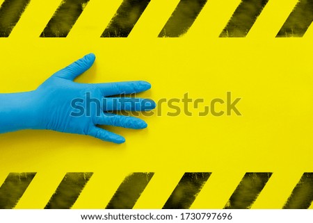 Hand in blue medical glove and  inscription on wooden cubes "Warning" on yellow background. World epidemic danger. Global pandemic. Radiation pollution.
