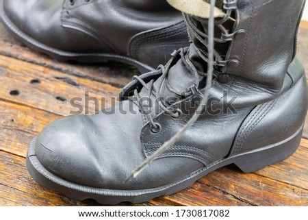 Black leather military combat boots on a wooden background.