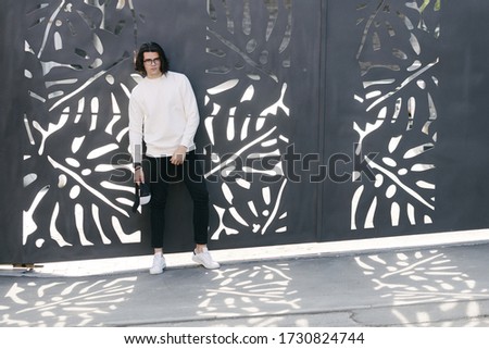 Man wearing white sweatshirt or hoodie and glasses outside on the city streets. Sweatshirt or hoodie for mock up, logo designs or design prints with free space