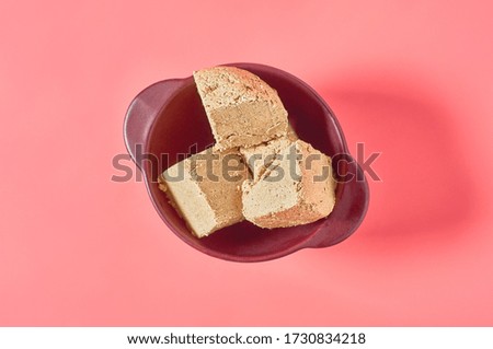 Pieces of sunflower halva lies in bowl on pink background. Turkish sweets
