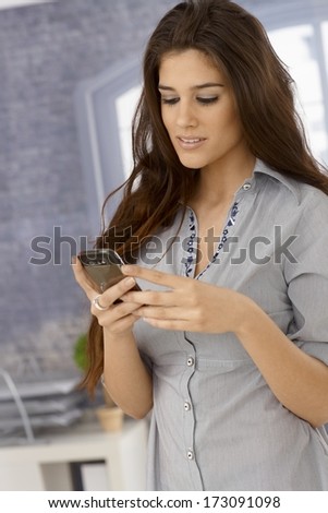 Attractive young woman using mobilephone, writing text message.