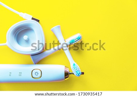 Modern rechargeable sonic or electric toothbrush set on pastel yellow flat lay background with copy space. Concept of professional oral care and healthy teeth by using ultrasonic toothbrush