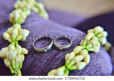 Groom and bride's wedding rings pictured on purple couch