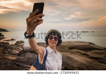 Female travelers take a picture with a smartphone in a seaside tourist spot