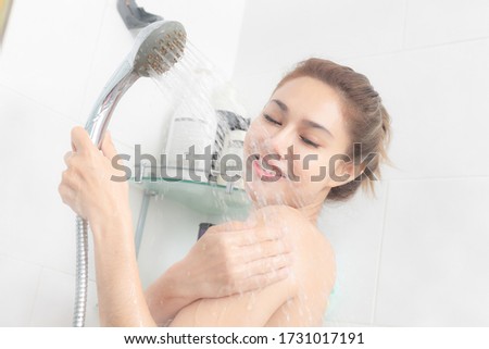 Portrait of happy woman taking shower with gel in bathroom.