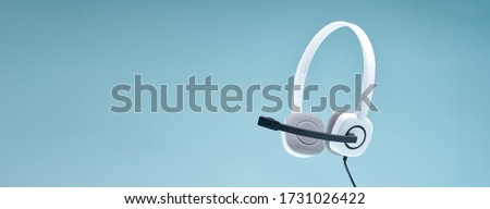Headphones with a microphone on blank blue background, place for text. Royalty-Free Stock Photo #1731026422