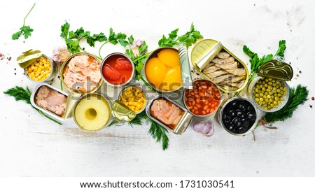 Food background in tin cans. Canned vegetables, beans, fish and fruits on a white wooden background. Top view. Royalty-Free Stock Photo #1731030541