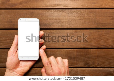 A top view of a set of wired earbud headphones and mobile phone blank template lying on a rustic wooden table. mockup image