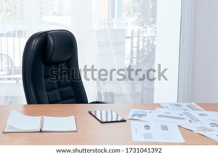 Manager desk and chair near window with note book tablet and sale document placing together