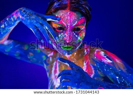 Body art glowing in ultraviolet light. Body art on the body and hand of a girl glowing in the ultraviolet light