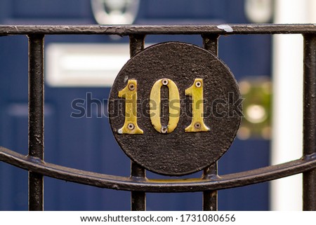 House number 101 on a black metal gate in front of a wooden front door