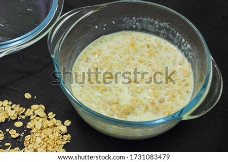 Microwave oatmeal porridge. A recipe for a quick and tasty breakfast. Glass bowl on a black table.
