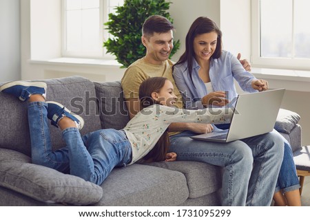 Family laptop online. Parents and a kid child look at a laptop at their leisure in a weekend at home.