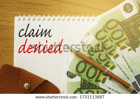 Claim Denied words on copybook page, 100 Euro bills, a pen and leather wallet on wooden table. Business sponsorship or insurance payment reject concept.