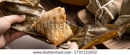 Rice dumpling zongzi eating - Young Asian woman is eating Chinese traditional food on wooden table at home for Dragon Boat Festival celebration, close up