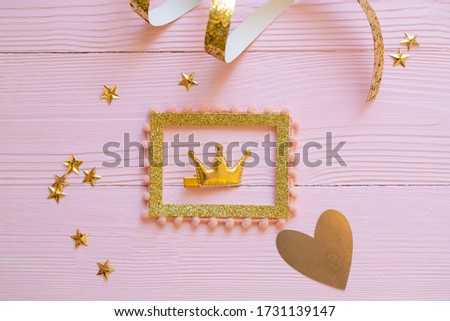 Bright children's hair accessories on a pink wooden background, Gold children's hair clip in the form of rabbit ears, pink wooden background, spangles stars on the background