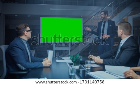 Late at Night In the Corporate Meeting Room: Director Talks and Uses Digital Chroma Key Interactive Whiteboard for Presentation to Executives, Investors. Green Mock-up Screen in Horizontal Mode