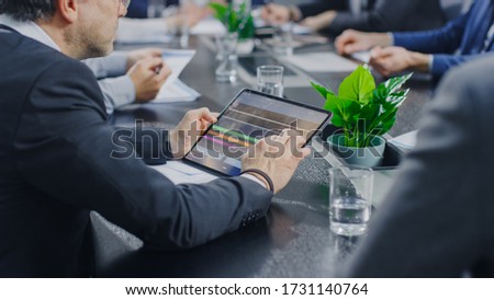 In the Corporate Meeting Room Close-up on the Hands of Businessperson Signing Contract. People Sitting at Conference Table