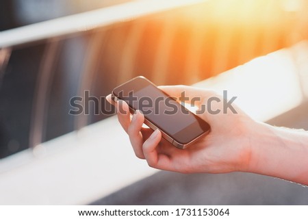 Man Hands holding a smartphone mockup on the street on sunset background